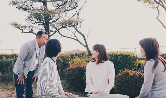 病院の庭でスタッフと患者が談笑している様子